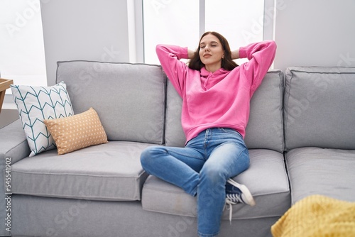 Young woman relaxed with hands on head sitting on sofa at home