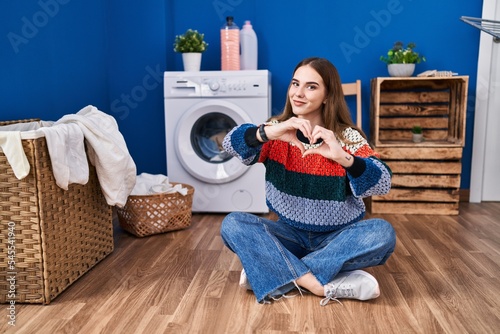 Young hispanic girl doing laundry smiling in love showing heart symbol and shape with hands. romantic concept.