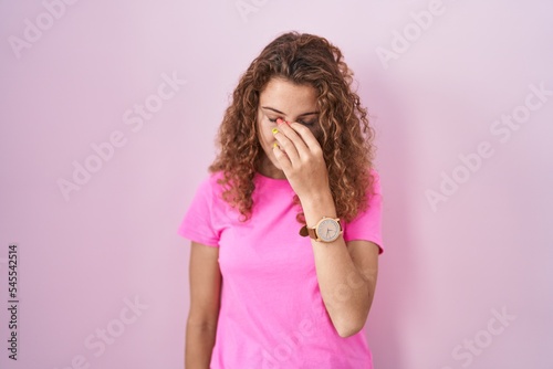 Young caucasian woman standing over pink background tired rubbing nose and eyes feeling fatigue and headache. stress and frustration concept.