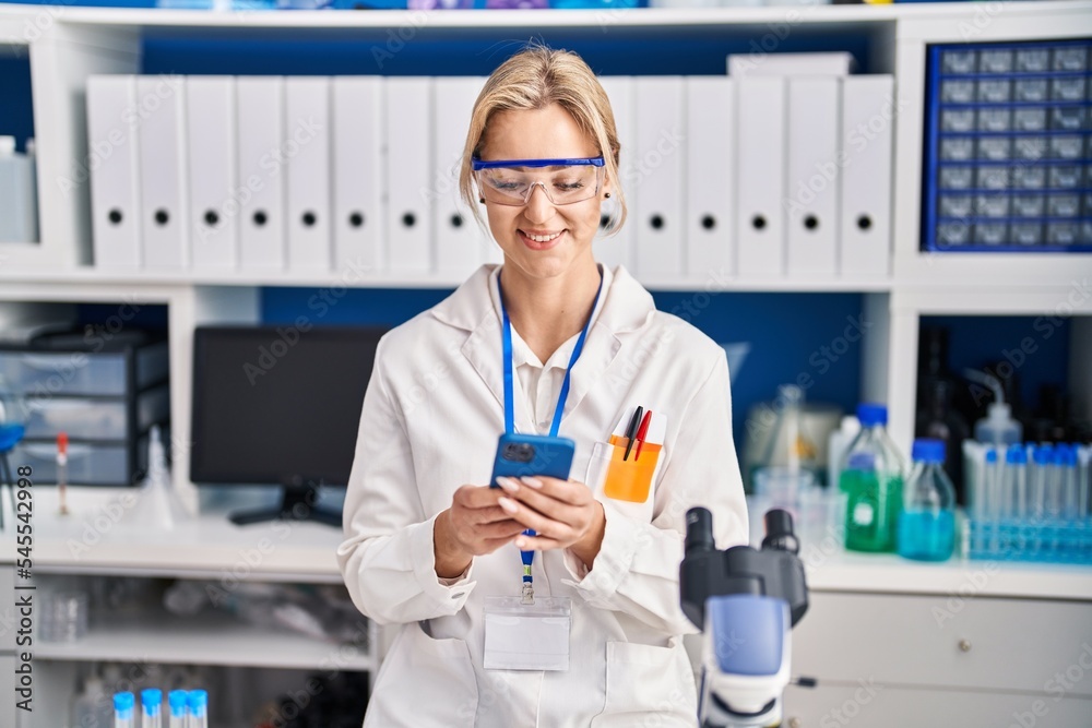 Young blonde woman scientist using smartphone at laboratory