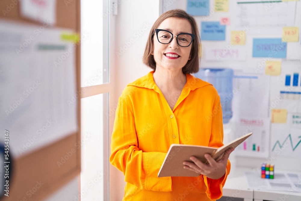Middle age woman business worker reading notebook at office Middle age woman business worker reading notebook at office
