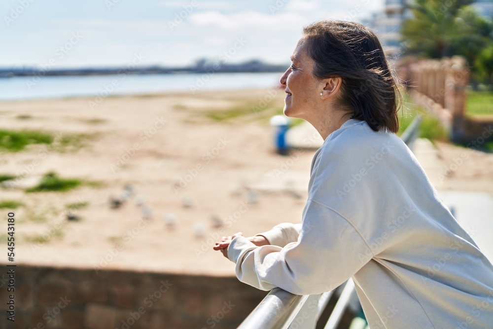Middle age woman smiling confident standing at seaside Middle age woman smiling confident standing at seaside