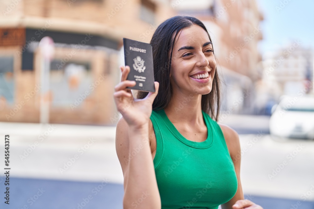 Young beautiful hispanic woman smiling confident holding united states passport at street