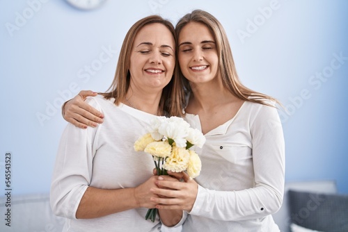 Two women mother and daughter surprise with flowers at home