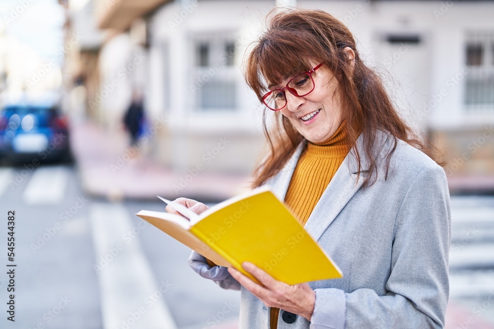 Middle age woman business executive reading book at street Middle age woman business executive reading book at street