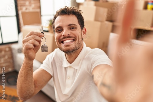 Young hispanic man make selfie by the camera holding key at new home