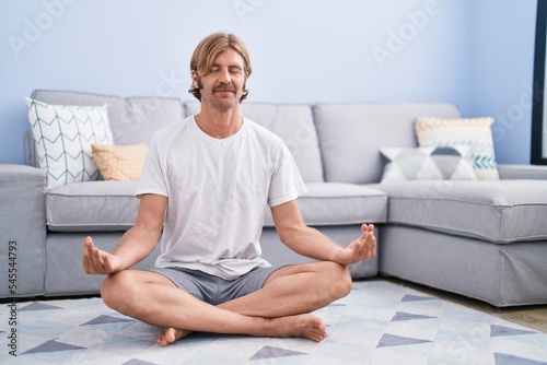Young blond man smiling confident training yoga at home
