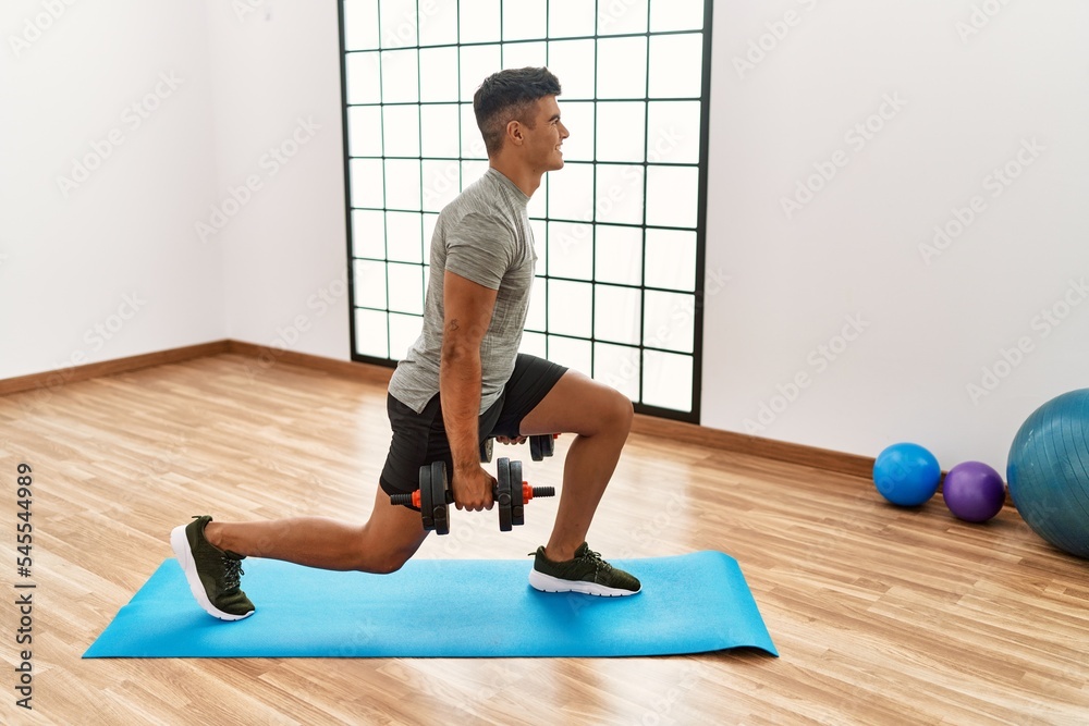 Young hispanic man smiling confident training using dumbbells at sport center Young hispanic man smiling confident training using dumbbells at sport center