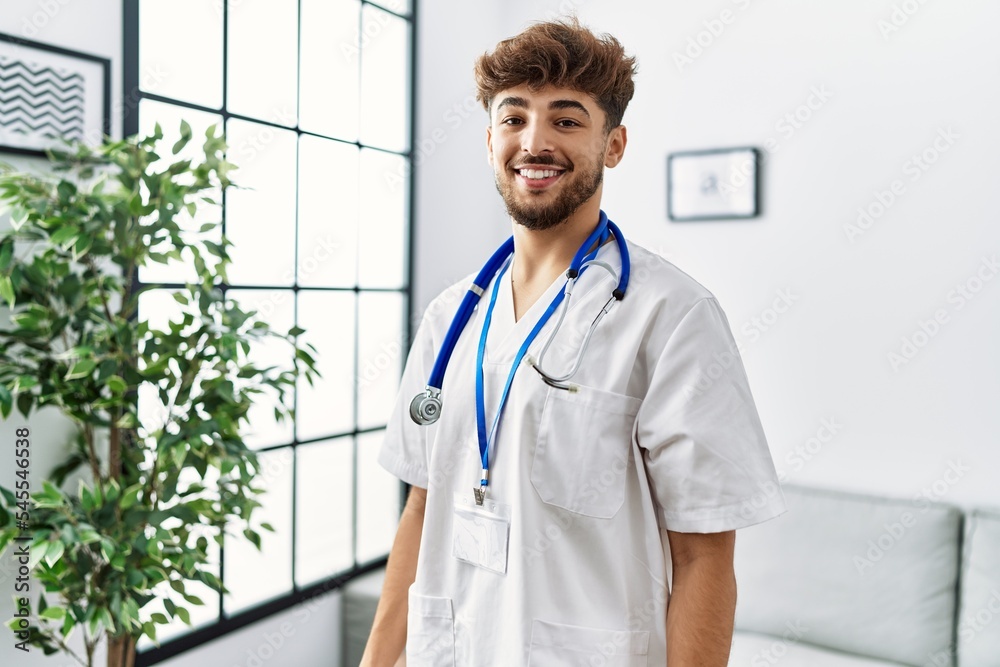 Young arab man wearing doctor uniform standing at clinic Young arab man wearing doctor uniform standing at clinic