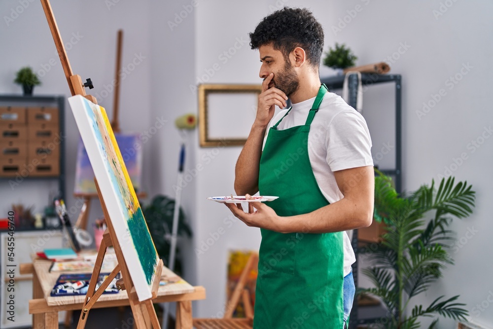 Young arab man artist looking drawi with doubt expression at art studio Young arab man artist looking drawi with doubt expression at art studio