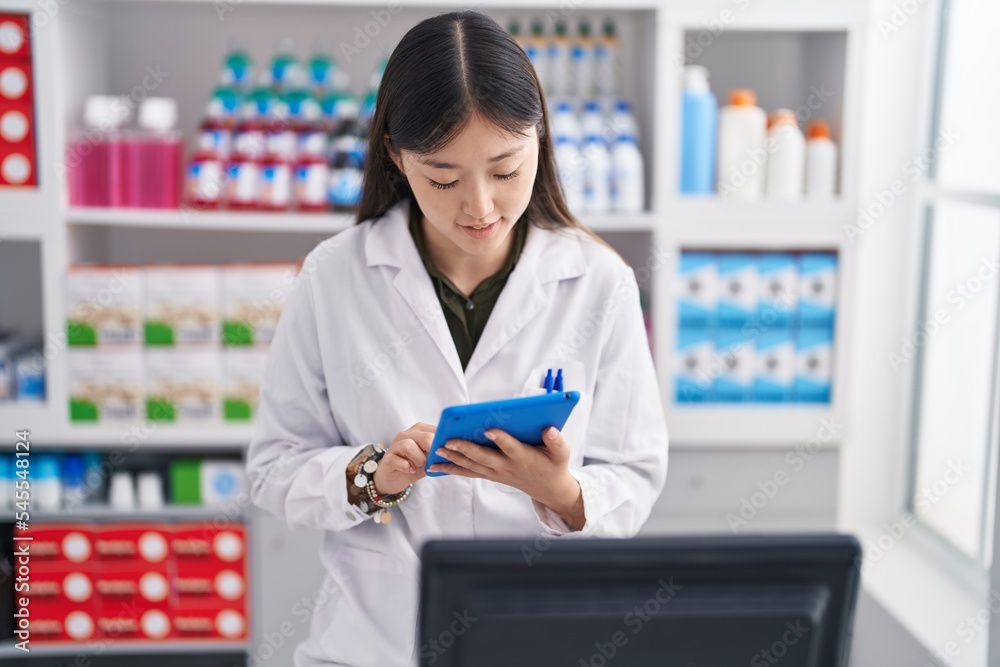 Chinese woman pharmacist using touchpad working at pharmacy