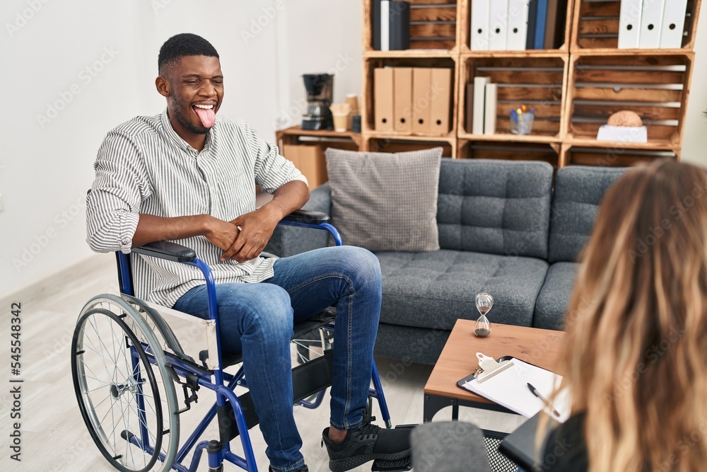 African american man doing therapy sitting on wheelchair sticking tongue out happy with funny expression. emotion concept.