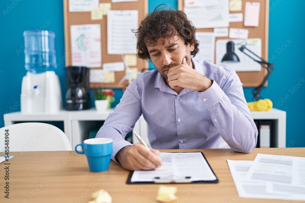 Young hispanic man business worker writing on documentuu at office Young hispanic man business worker writing on documentuu at office