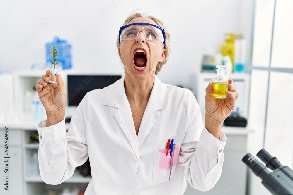 Middle age blonde woman working at laboratory angry and mad screaming frustrated and furious, shouting with anger looking up. Middle age blonde woman working at laboratory angry and mad screaming frustrated and furious, shouting with anger looking up.