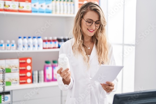 Free Download Young woman pharmacist reading prescription holding pills bottle at pharmacy - GFXLoad