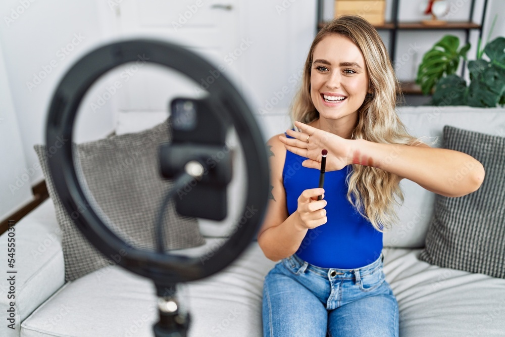 Young woman recording makeup tutorial by smartphone at home Young woman recording makeup tutorial by smartphone at home