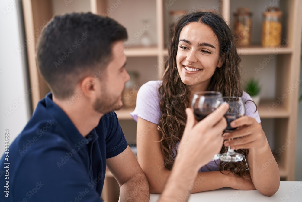 Young hispanic couple drinking wine sitting on table at home Young hispanic couple drinking wine sitting on table at home