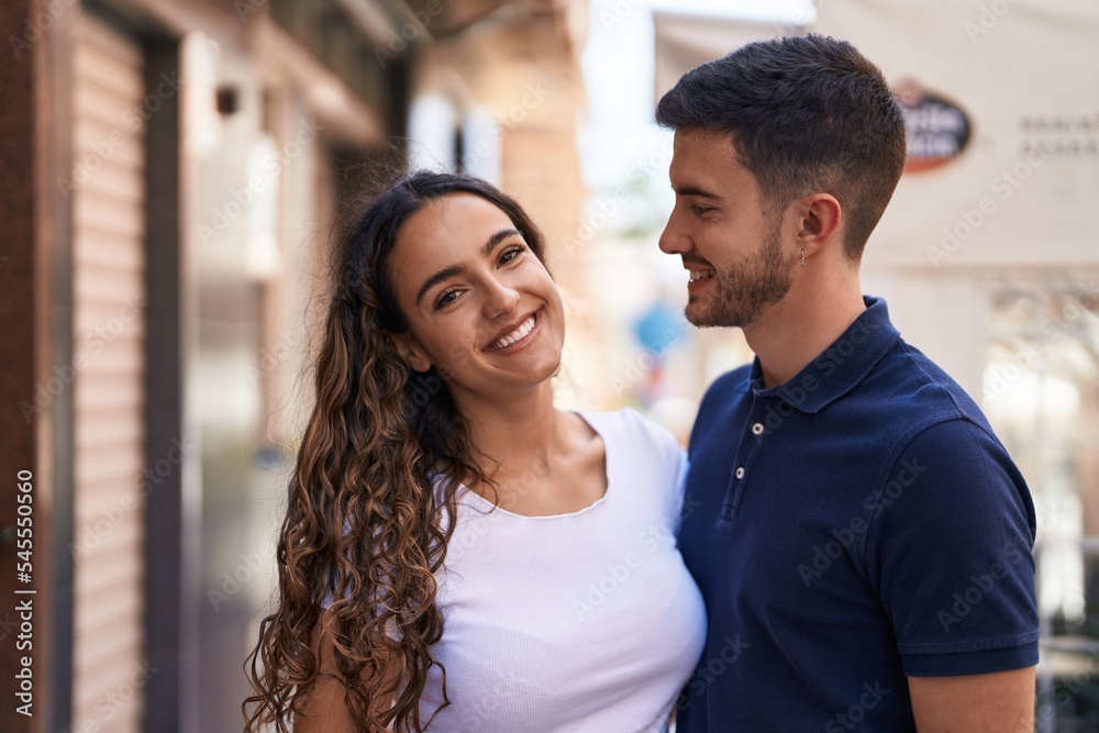 Fototapeta premium Young hispanic couple smiling confident hugging each other at street