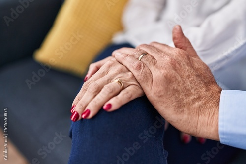 Middle age man and woman couple showing engagement ring sitting on sofa at home © Krakenimages.com