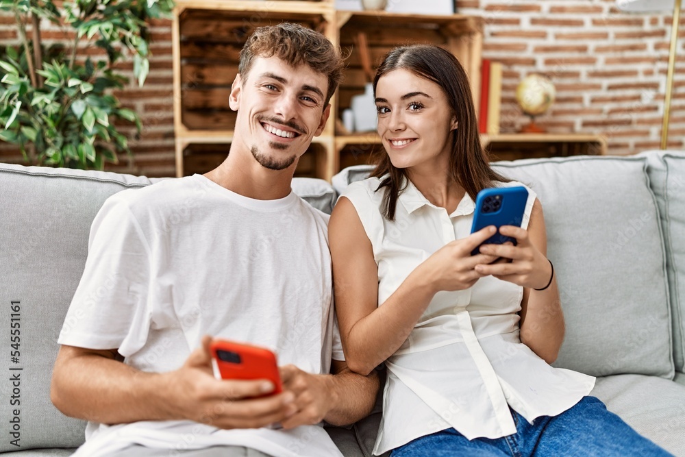 Man and woman couple smiling confident using smartphone at home Man and woman couple smiling confident using smartphone at home