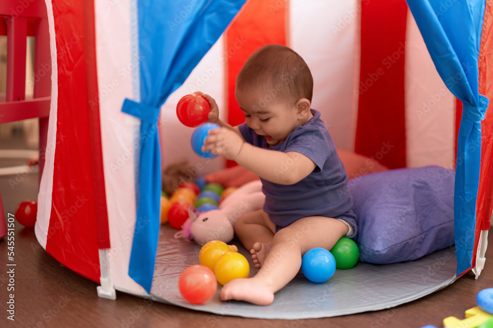 Obraz premium Adorable chinese toddler playing with balls sitting inside of circus tent at home