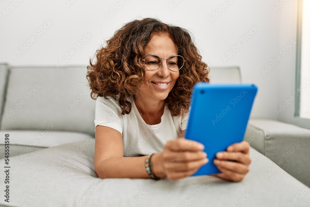 Middle age hispanic woman smiling confident using touchpad at home Middle age hispanic woman smiling confident using touchpad at home