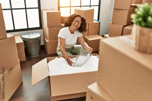 Middle age hispanic woman smiling confident moving at new home