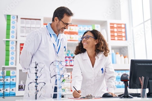 Man and woman pharmacists writing on document working at pharmacy
