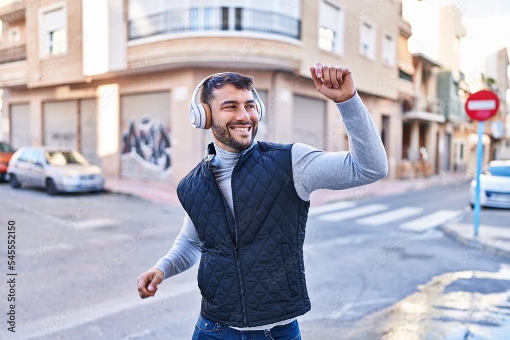 Fototapeta premium Young hispanic man smiling confident listening to music at street
