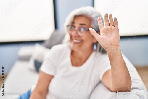 Middle age woman sitting on sofa speaking at home