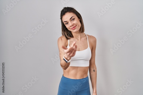 Hispanic woman wearing sportswear over isolated background beckoning come here gesture with hand inviting welcoming happy and smiling © Krakenimages.com