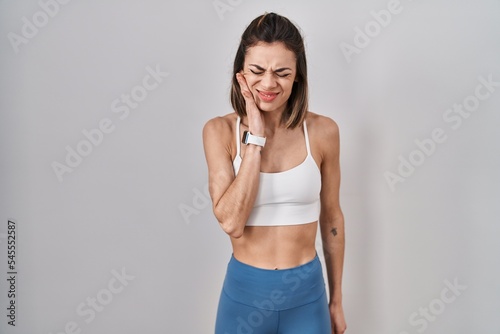 Hispanic woman wearing sportswear over isolated background touching mouth with hand with painful expression because of toothache or dental illness on teeth. dentist © Krakenimages.com
