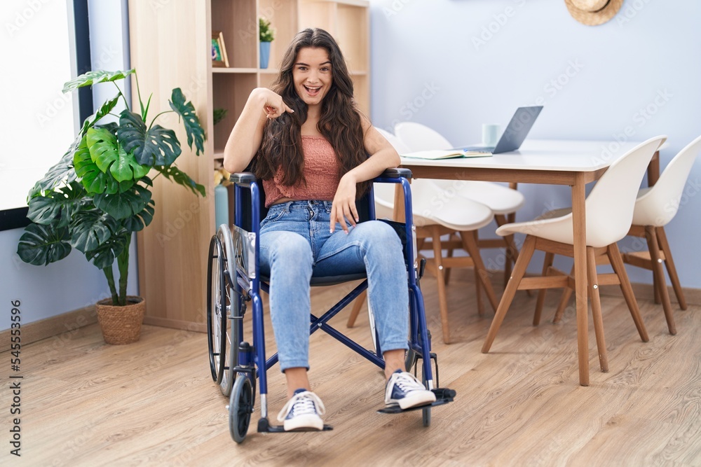 Young teenager girl sitting on wheelchair at the living room pointing finger to one self smiling happy and proud Young teenager girl sitting on wheelchair at the living room pointing finger to one self smiling happy and proud