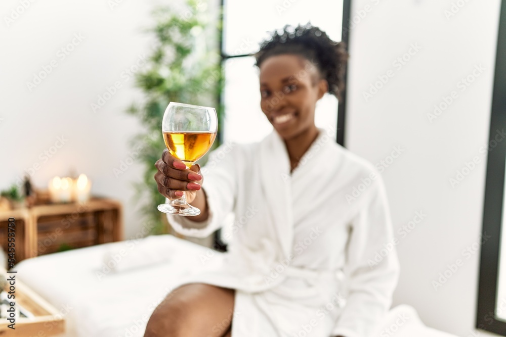 African american woman wearing bathrobe drinking champagne at beauty salon African american woman wearing bathrobe drinking champagne at beauty salon
