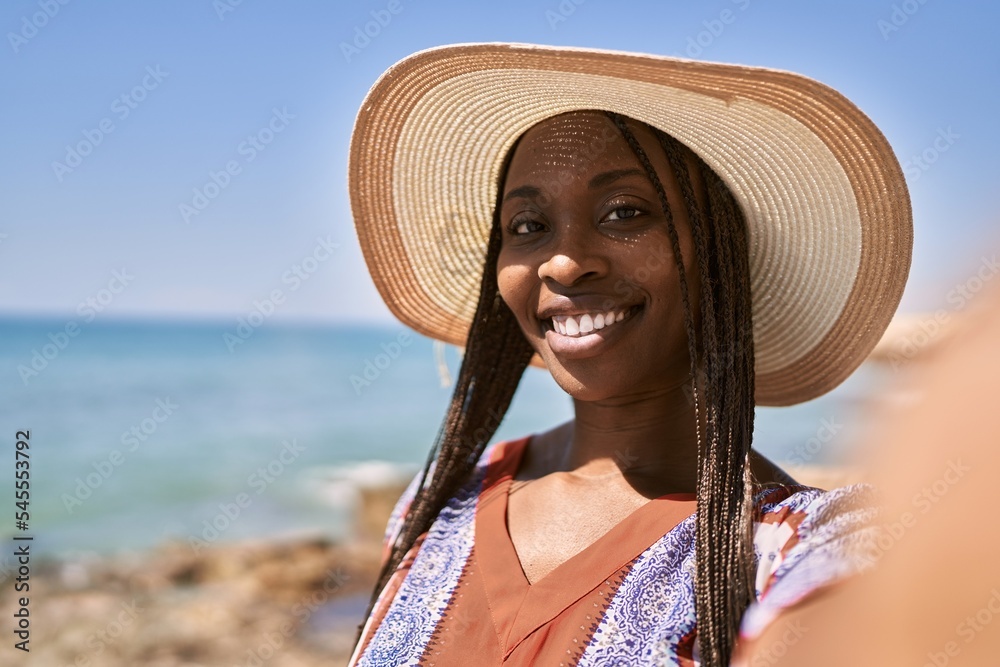 Young african american woman make selfie by the camera at the beach.