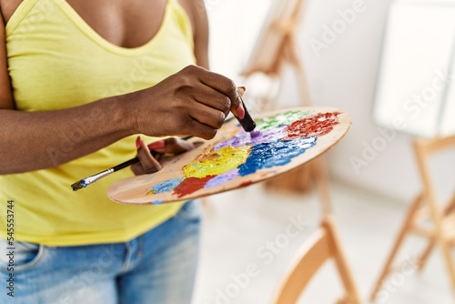 African american artist woman mixing color on palette at art studio.