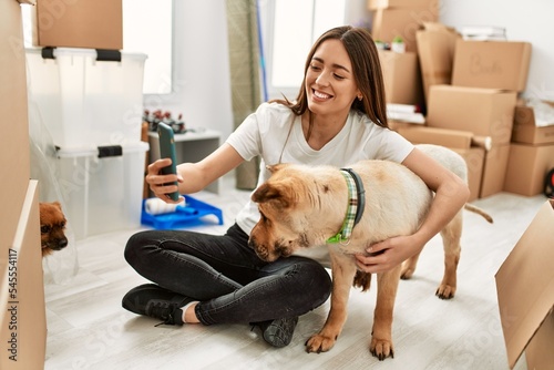 Young hispanic woman smiling confident make selfie by the smartphone sitting on floor at new home