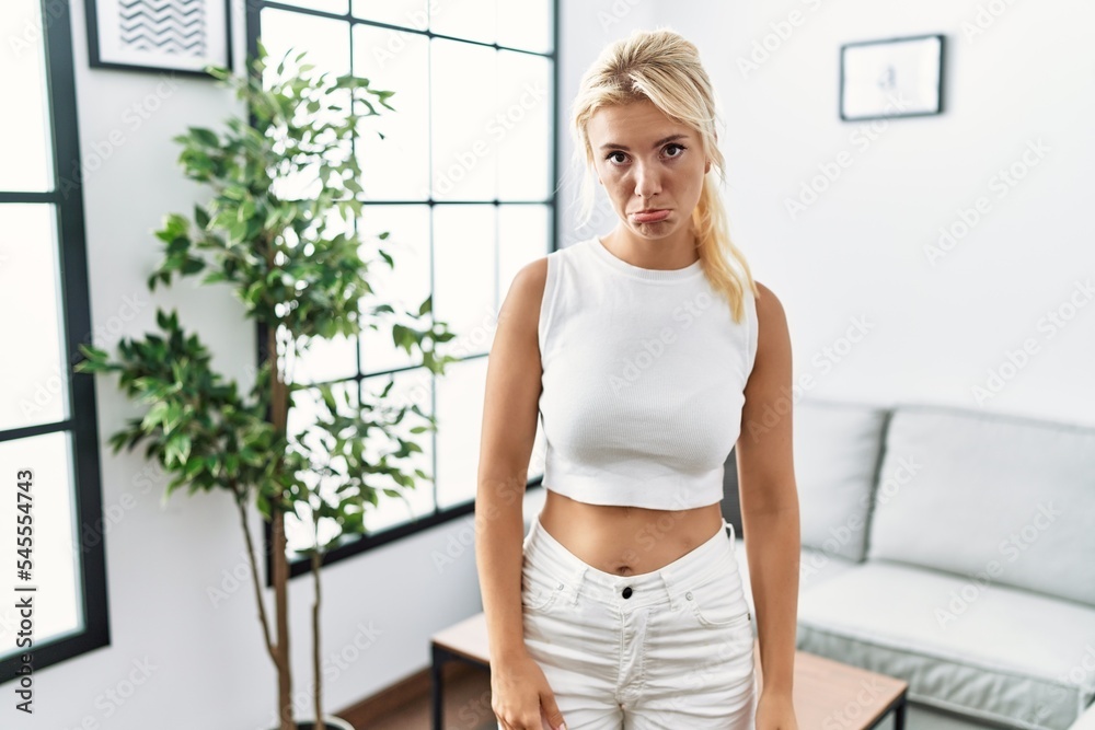 Young caucasian woman standing at living room depressed and worry for distress, crying angry and afraid. sad expression.