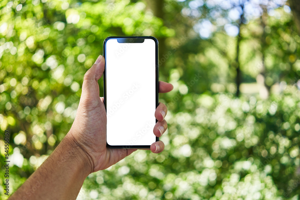 Man holding smartphone showing white blank screen at park Man holding smartphone showing white blank screen at park