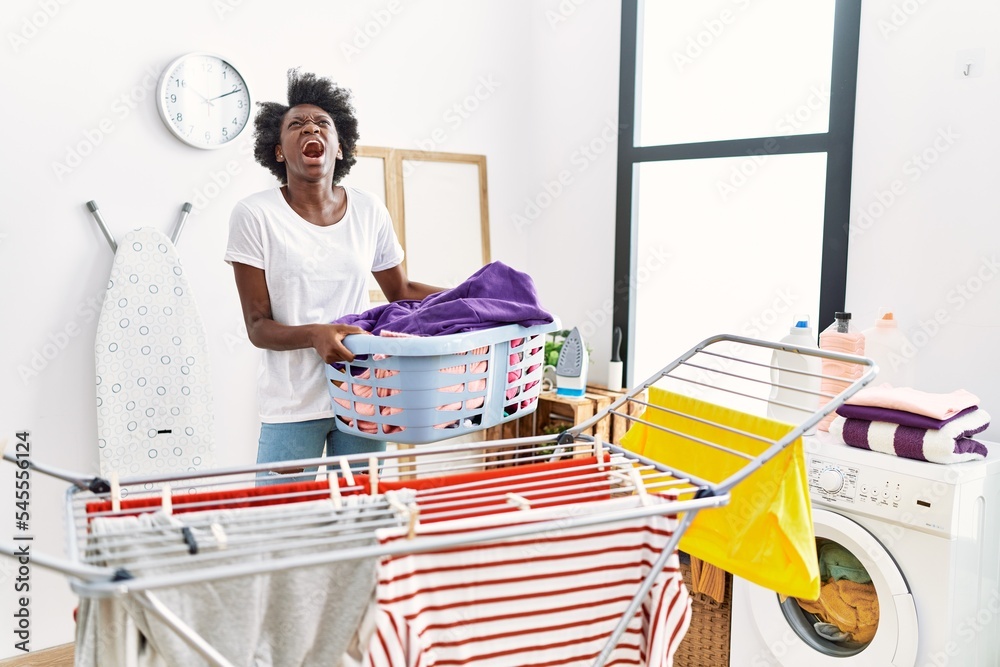 African young woman doing laundry at clothesline angry and mad screaming frustrated and furious, shouting with anger looking up. African young woman doing laundry at clothesline angry and mad screaming frustrated and furious, shouting with anger looking up.