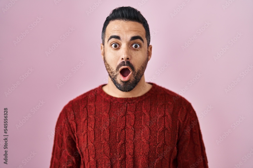 Young hispanic man with beard wearing casual sweater over pink background afraid and shocked with surprise expression, fear and excited face. Young hispanic man with beard wearing casual sweater over pink background afraid and shocked with surprise expression, fear and excited face.