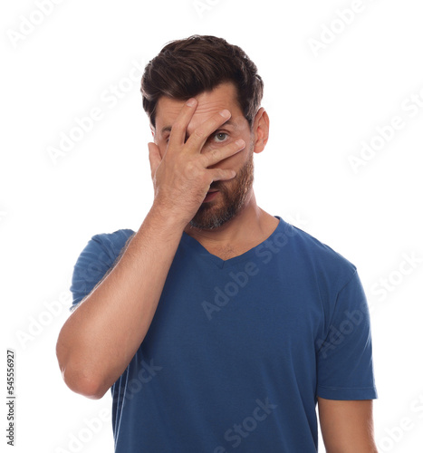 Embarrassed man covering face with hand on white background