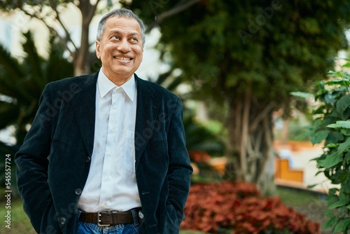 Middle age southeast asian man standing and smiling confident by the park