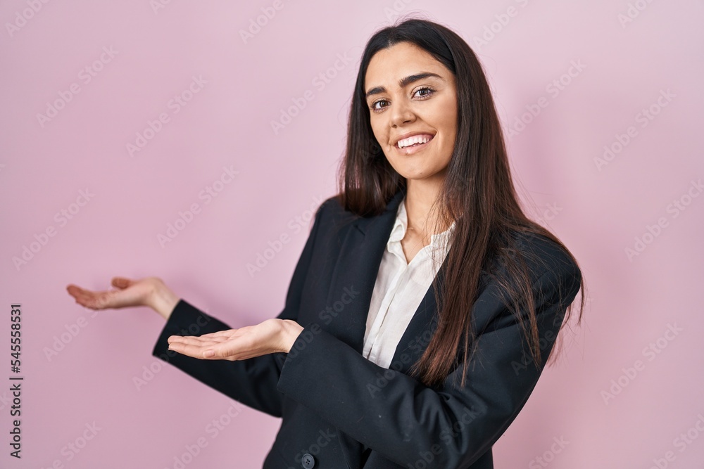 Young brunette woman wearing business style over pink background inviting to enter smiling natural with open hand Young brunette woman wearing business style over pink background inviting to enter smiling natural with open hand