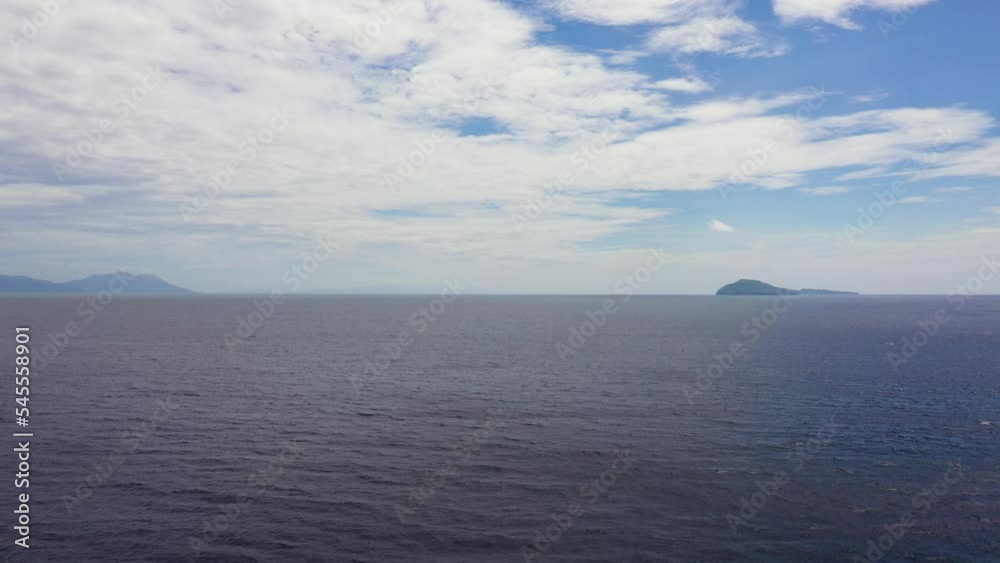 Tropical blue sea and blue sky with clouds. Mountains on the horizon. Seascape, aerial view. Flight over the sea. Summer and travel vacation concept. Tropical blue sea and blue sky with clouds. Mountains on the horizon. Seascape, aerial view. Flight over the sea. Summer and travel vacation concept.