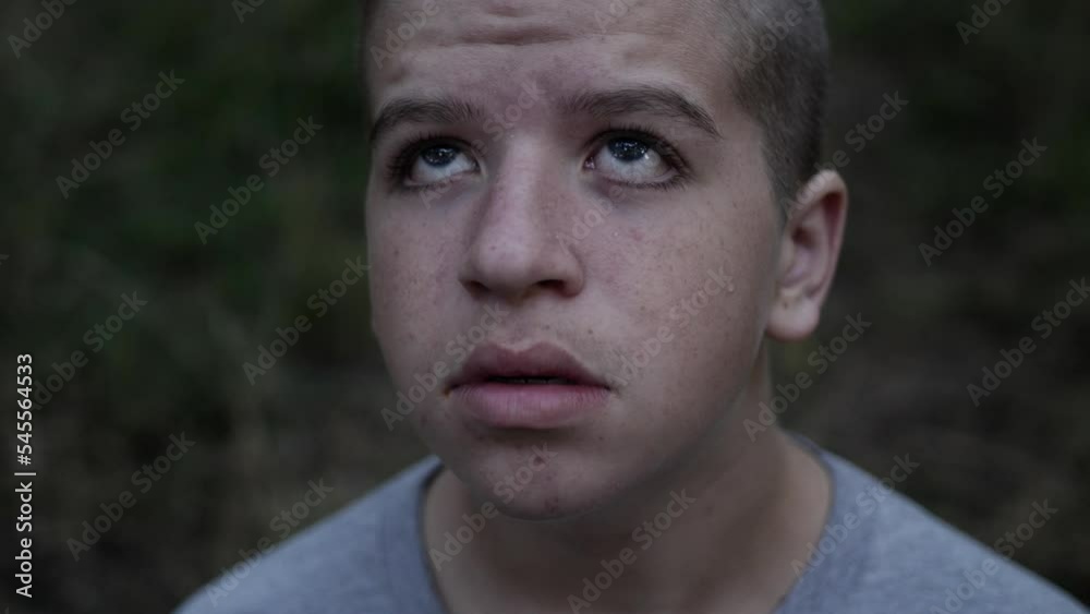 A sad, lonely, depressed looking, young, teenage boy in the forest looks up at God in the sky praying and looking for help A sad, lonely, depressed looking, young, teenage boy in the forest looks up at God in the sky praying and looking for help