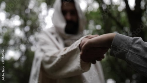 Jesus Christ takes the hand of a young man to help them stand up photo