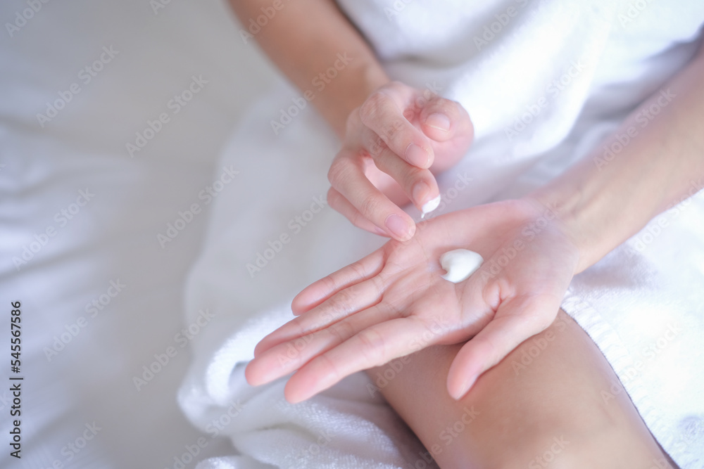 Asia woman sitting on bed and applying cream on Hand. Asia woman sitting on bed and applying cream on Hand.