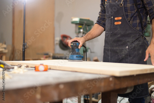 Carpenter man professional skill using electric sander for wood in carpentry shop photo