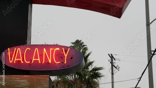 Red neon sign Vacancy glowing, motel or hotel on road in California USA. Illuminated text about lodging during road trip. Tourism or traveling in America.